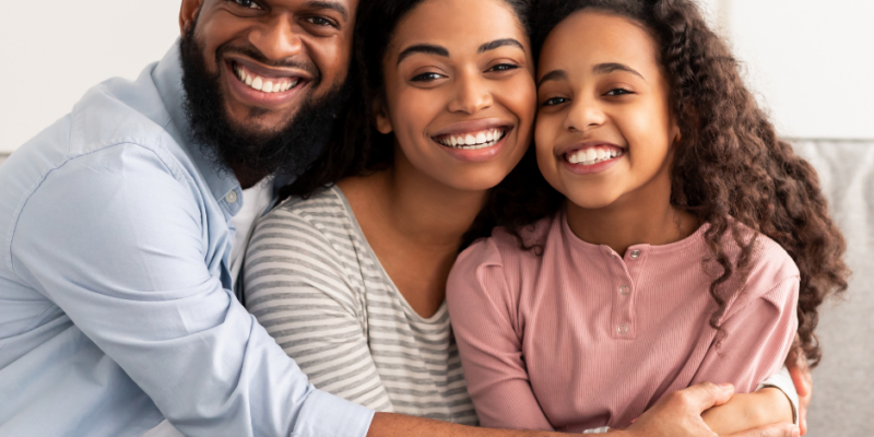 family with great smiles embraces each other